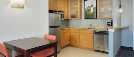 Cozinha compacta com armários de madeira, micro-ondas embutido e lava-louças.