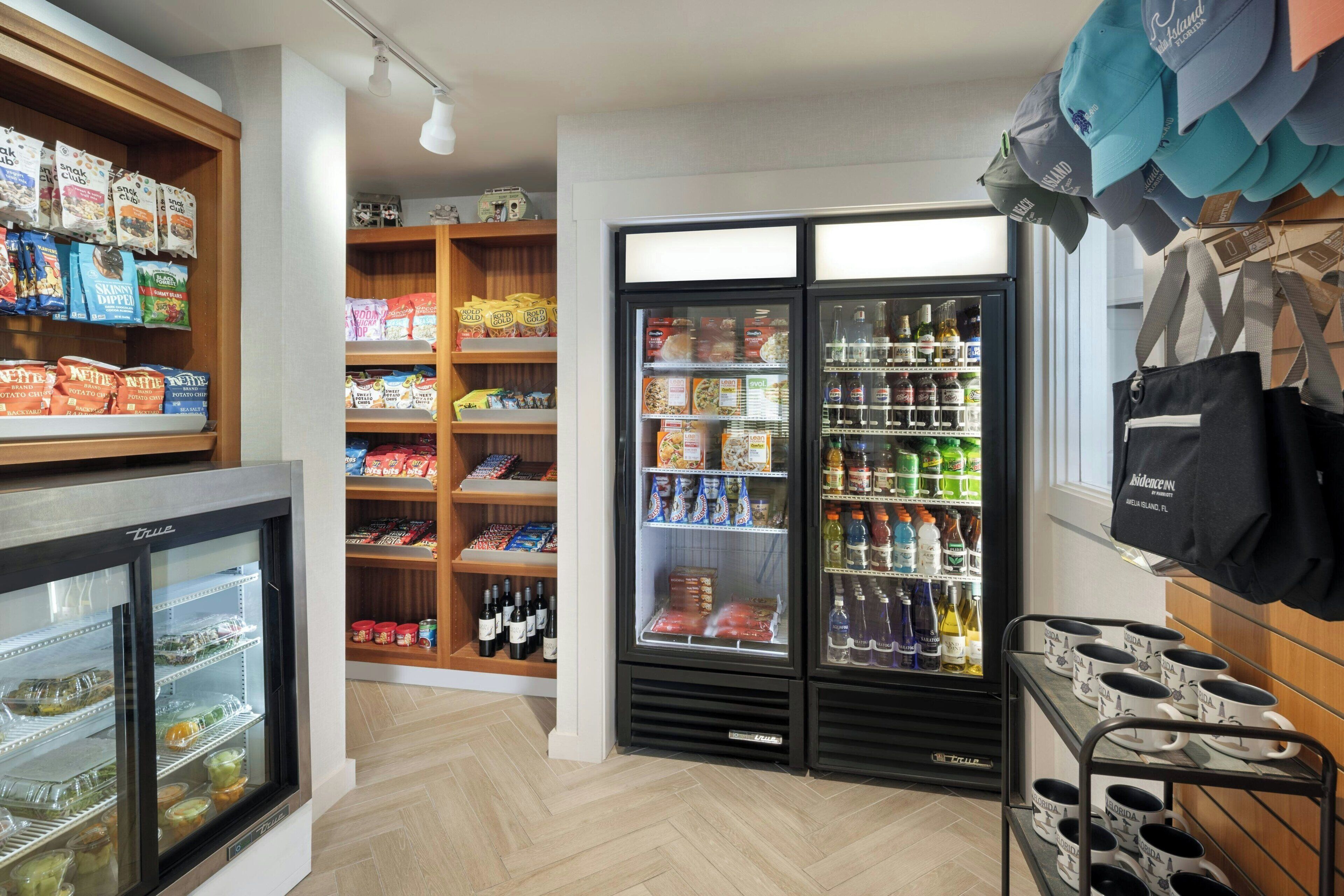 Un negozio di alimentari con reparti refrigerati, scaffali pieni di snack e una vetrina con cappelli.