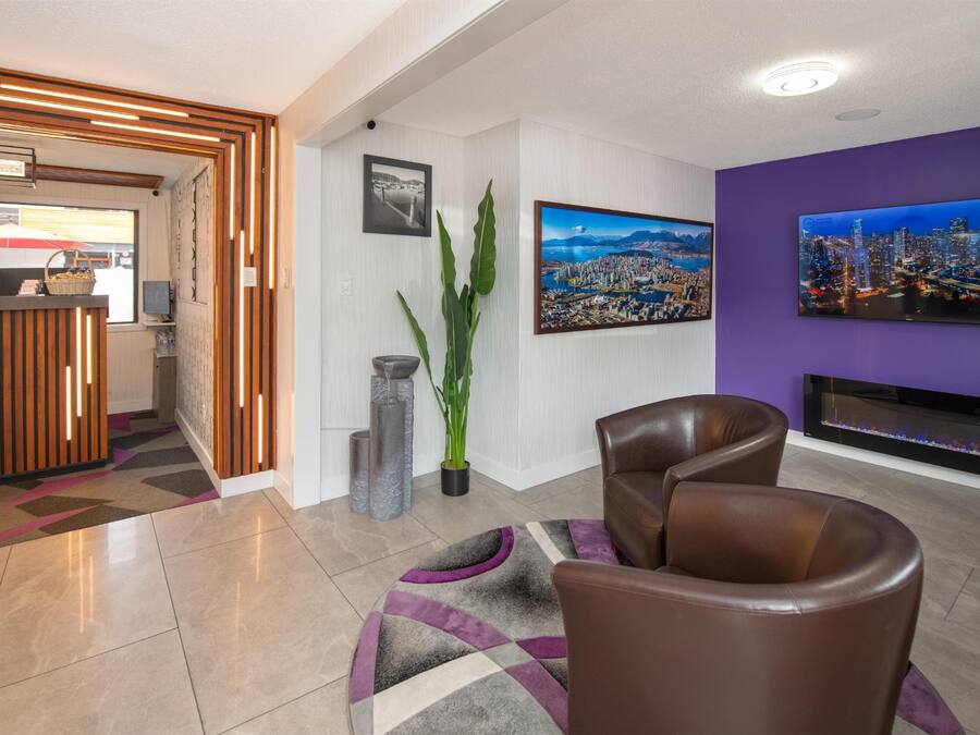 A modern living room with a reception desk, two leather chairs, a large flat-screen TV, and a fireplace.