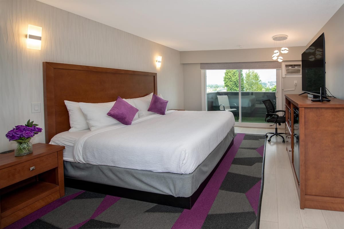 Una habitación de hotel moderna con una cama grande, un escritorio y vistas al exterior.