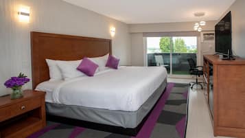 A modern hotel room with a large bed, a desk, and a view of the outdoors.