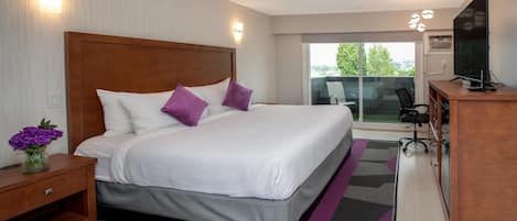 Quarto de hotel moderno com uma cama grande, uma mesa de trabalho e vista para o exterior.