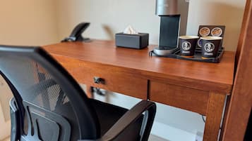 A wooden desk with a coffee maker, a tissue box, and two coffee cups.