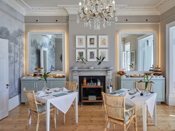 A dining room with a fireplace, framed artwork, and a chandelier. - Dock House Boutique Hotel & Spa by NEWMARK (Cape Town)