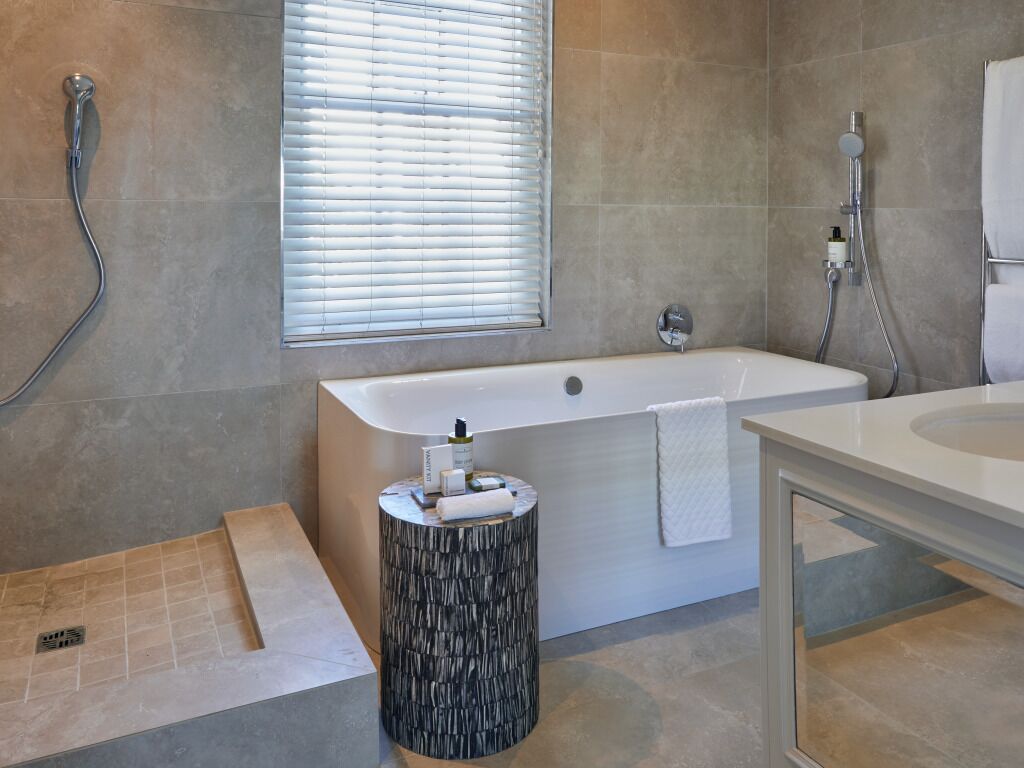 Une salle de bain moderne équipée d’une baignoire, d’une douche et d’un meuble-lavabo avec un miroir.