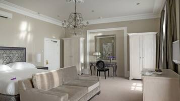 A hotel room with a bed, a sofa, a desk, and a mirror.