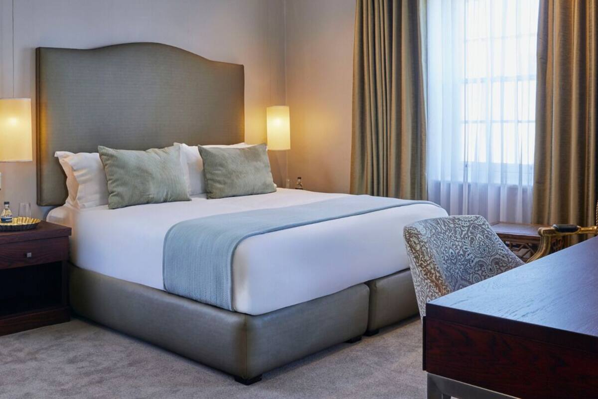 Ein Hotelzimmer mit einem großen Bett, Nachttischen, einem Schreibtisch und einem Stuhl.