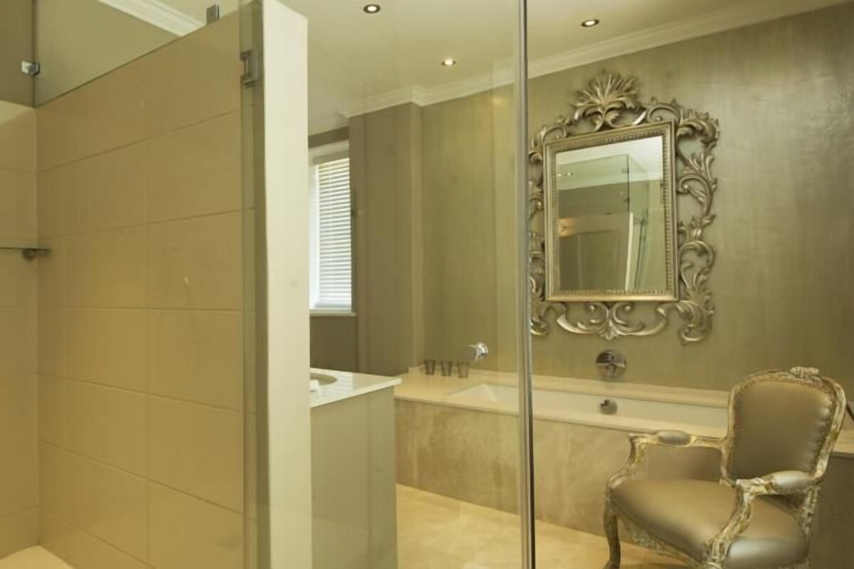 Une salle de bain avec une douche à parois de verre, une baignoire et un meuble-lavabo avec un miroir.