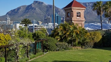 Un giardino con una torre a tetto rosso, palme e uno skyline con montagne sullo sfondo.