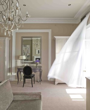 Una habitación con candelabro, escritorio, silla y un espejo grande.