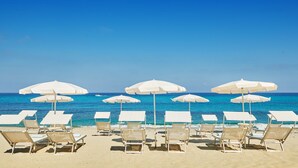 A beach with white umbrellas and lounge chairs arranged for sunbathing. - Capovaticano Resort Thalasso Spa (Ricadi)
