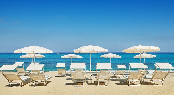 Privatstrand, weißer Sandstrand, Liegestühle, Sonnenschirme