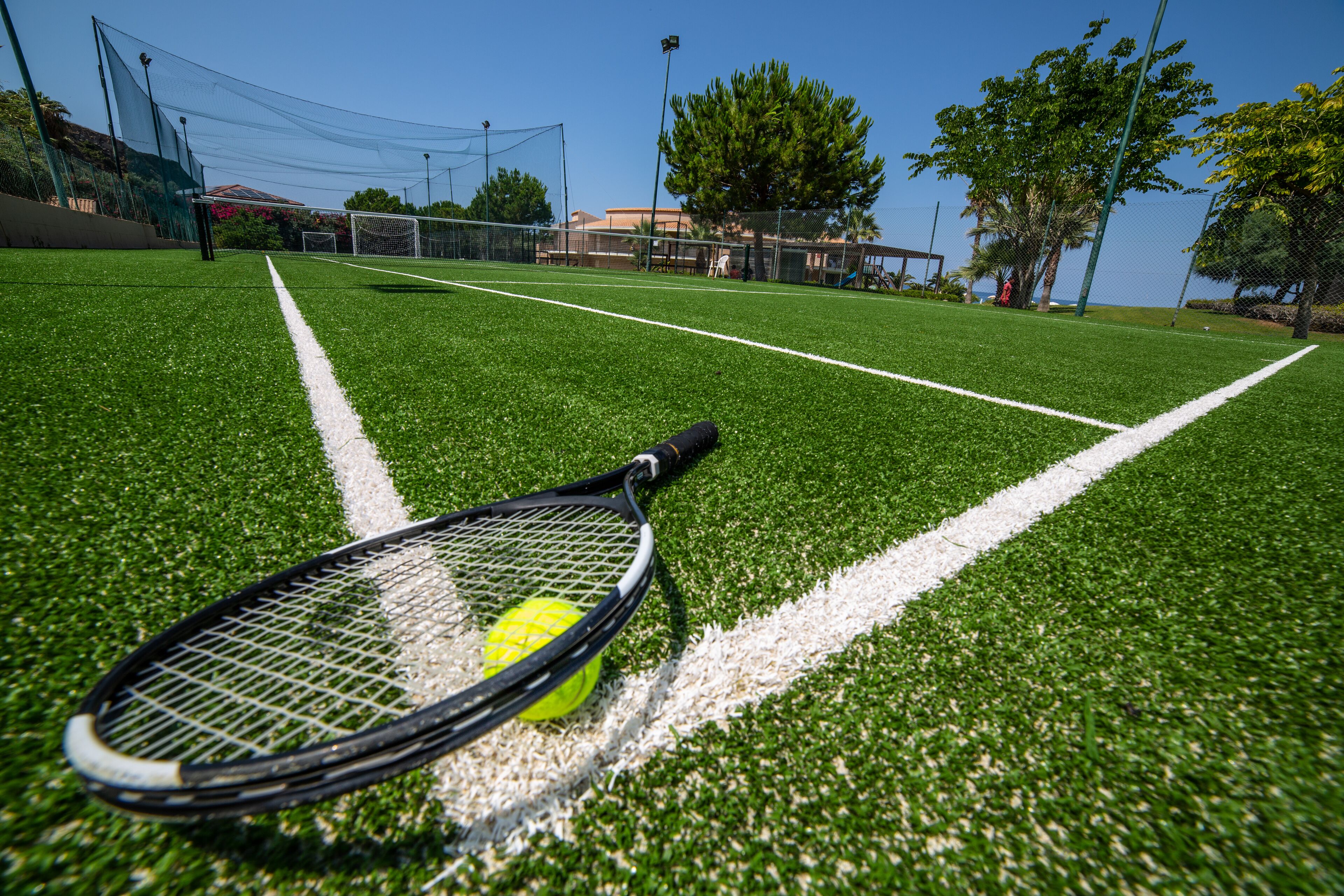 A tennis court with a net, a tennis ball, and a racket.