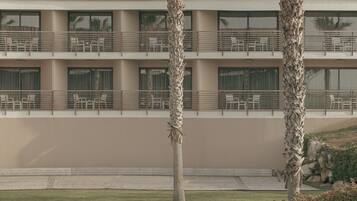 Un hotel con techo plano, varios balcones y palmeras al frente.