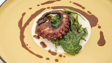 A plate with octopus, greens, and sauce.