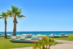 A beachside lounge area with palm trees and lounge chairs. - Capovaticano Resort Thalasso Spa (Ricadi)