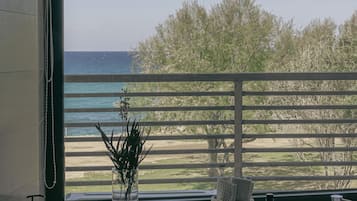 Un baño con un ventanal grande con vista a una playa y árboles.