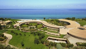 A resort with a curved building, a pool area, and a view of the sea. - Capovaticano Resort Thalasso Spa (Ricadi)