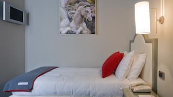 Camera d'albergo con un letto, un comodino, un telefono, una lampada e un quadro di un cavallo.