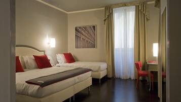 A hotel room with two beds, a desk, and a chair.