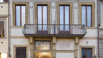 A historic building with ornate architectural details, a central entrance, and a balcony.