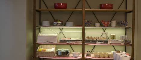 Un'area pranzo con tavolo in legno, sedie e un buffet che offre diversi cibi e piatti.