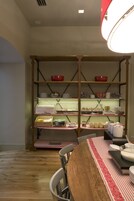 A dining area with a wooden table, chairs, and a buffet counter with various food items and dishes.