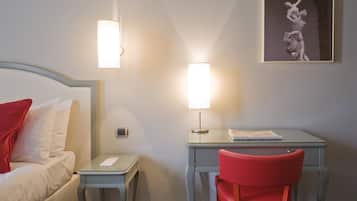 A hotel room with a bed, a desk, a chair, and a wall-mounted lamp.