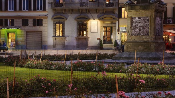 A hotel with a central monument, balconies, and a garden with pink flowers. - Hotel Rosso 23 (Florence)