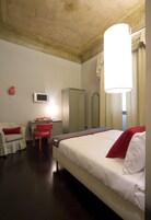 Een hotelkamer met een bed, een bureau met stoel, een televisie en een kledingkast.