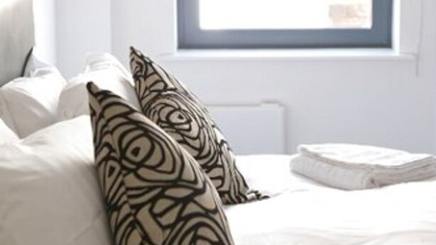 A bedroom with a bed, white bedding, and a window with a view.