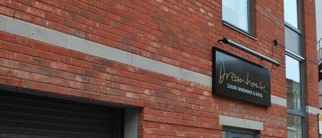 A brick building with a sign for 'Dreamhouse Luxury Apartments & Suites'.