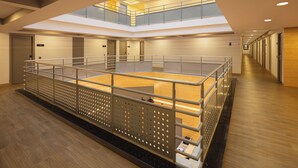 Un espacio interior amplio con un entrepiso, suelo de madera y barandillas de metal.