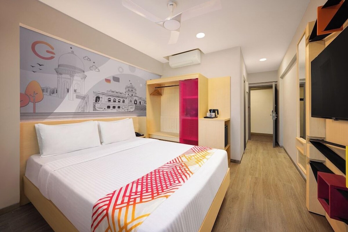 Une chambre d’hôtel avec un lit, une fresque murale, une armoire et un téléviseur.