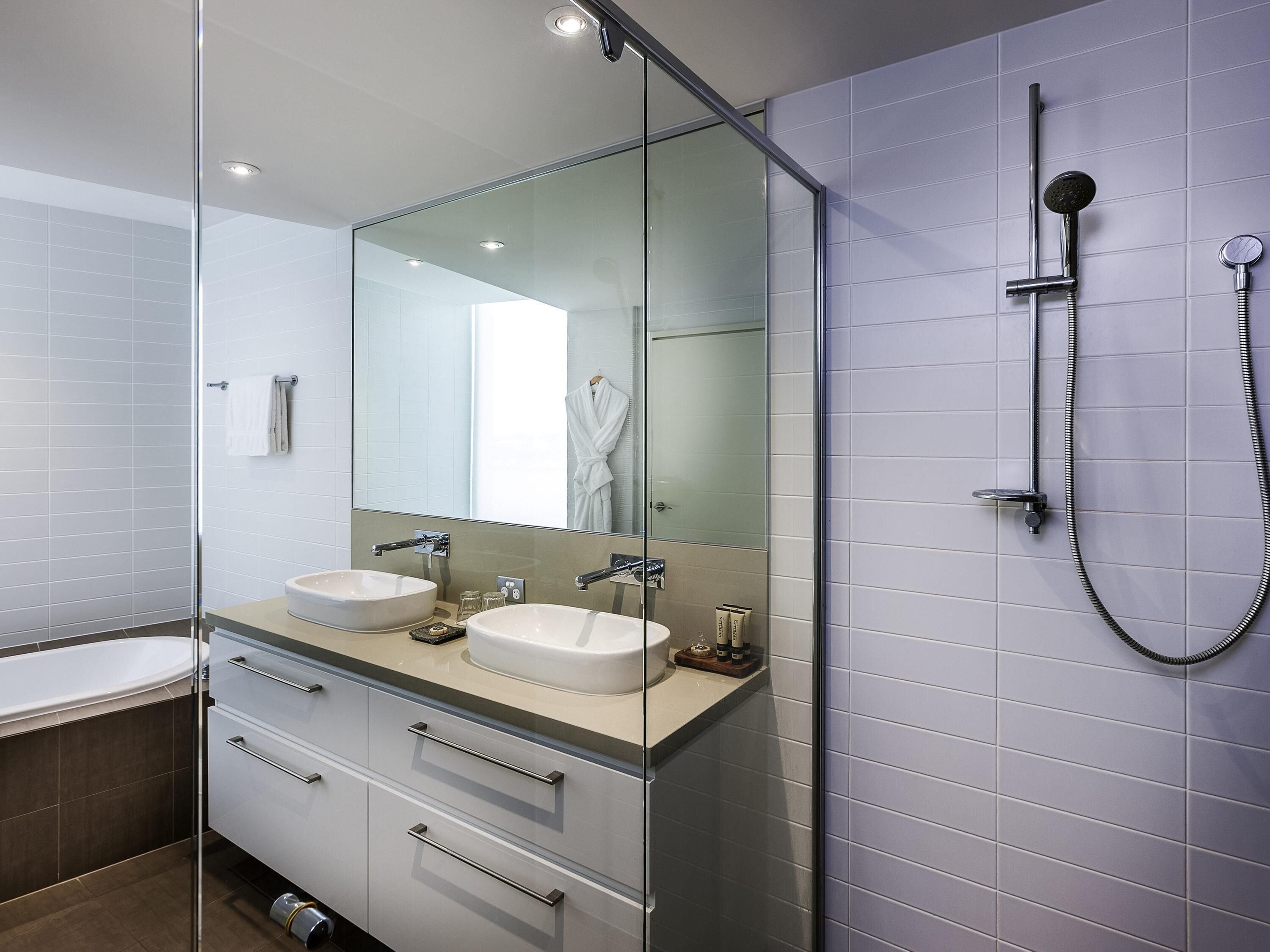 Un bagno moderno con due lavandini, un grande specchio e una doccia.