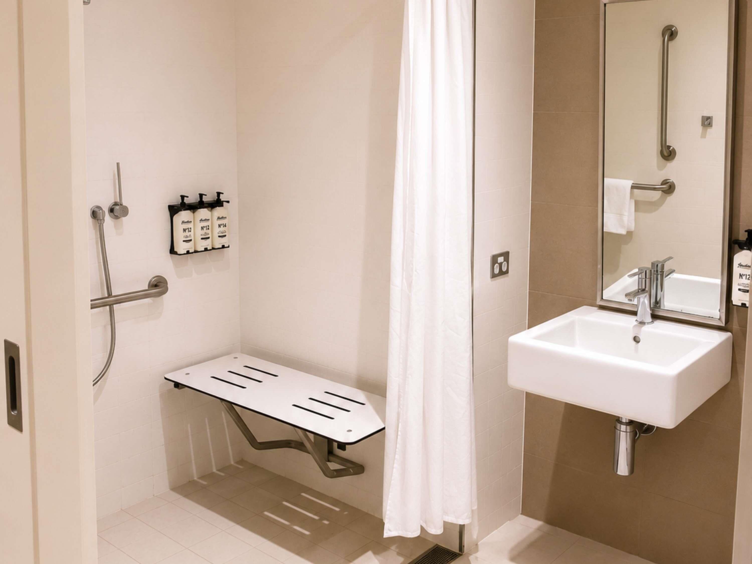 A bathroom with a shower, a sink, a mirror, and a towel rack.