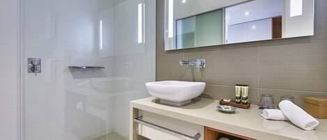 A modern bathroom with a large mirror, a white sink, and a shower area.