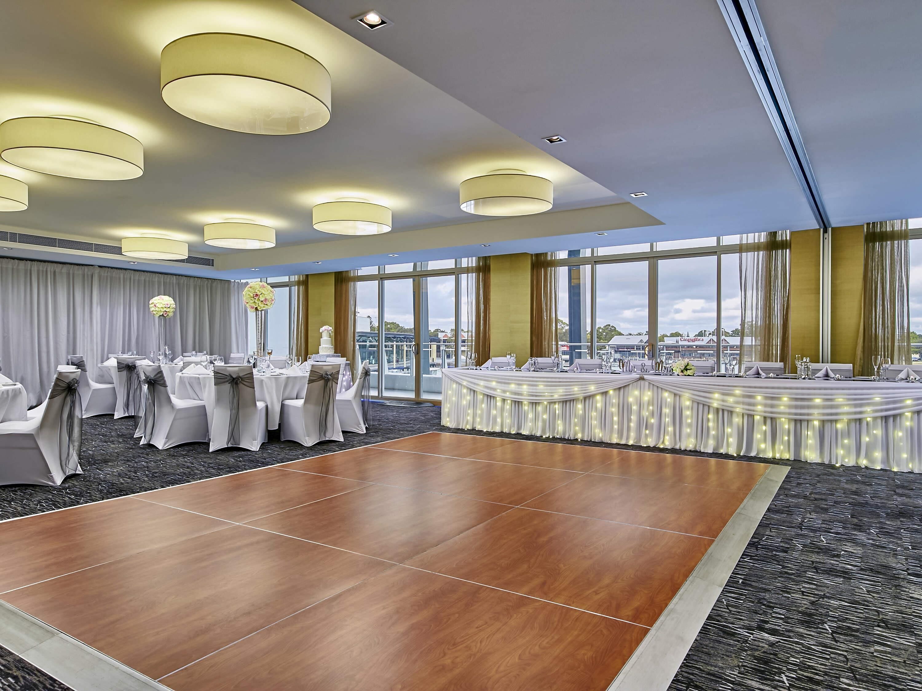 A conference room with round tables, chairs, and a dance floor.