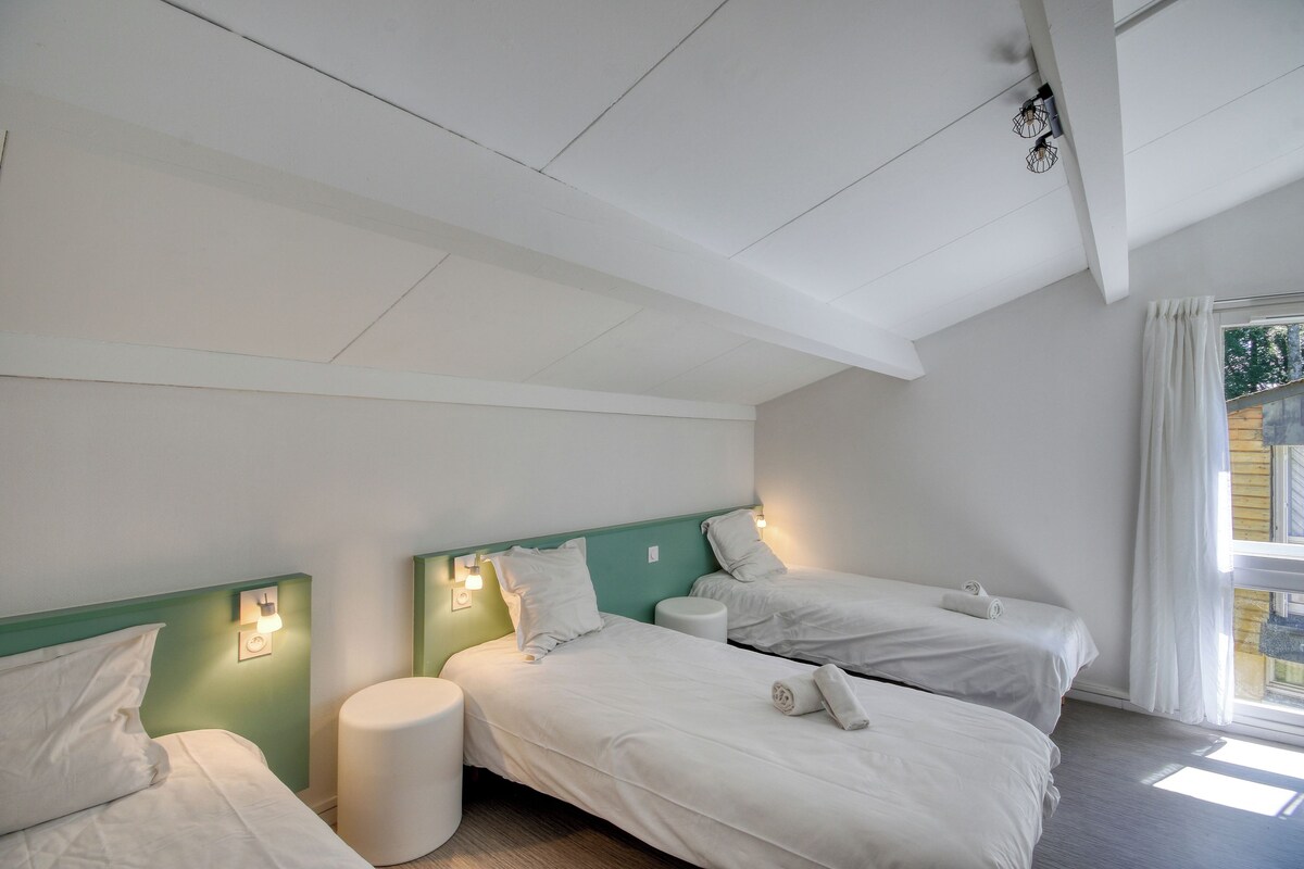 A room with two beds, a small round table, and a window with curtains.