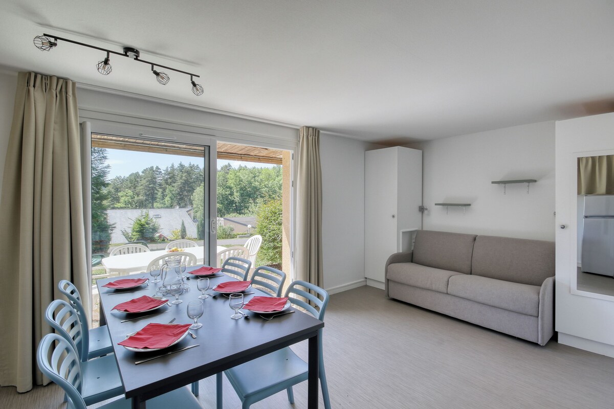 A dining area with a table set for four, a sofa, and a window with curtains.