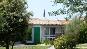 Une maison avec un toit en tuiles, une porte verte et un chemin qui y mène.