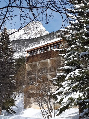 A building with a wooden facade and a balcony overlooking a snowy landscape with mountains in the background. - VVF Queyras, Ceillac-en-Queyras (Ceillac)