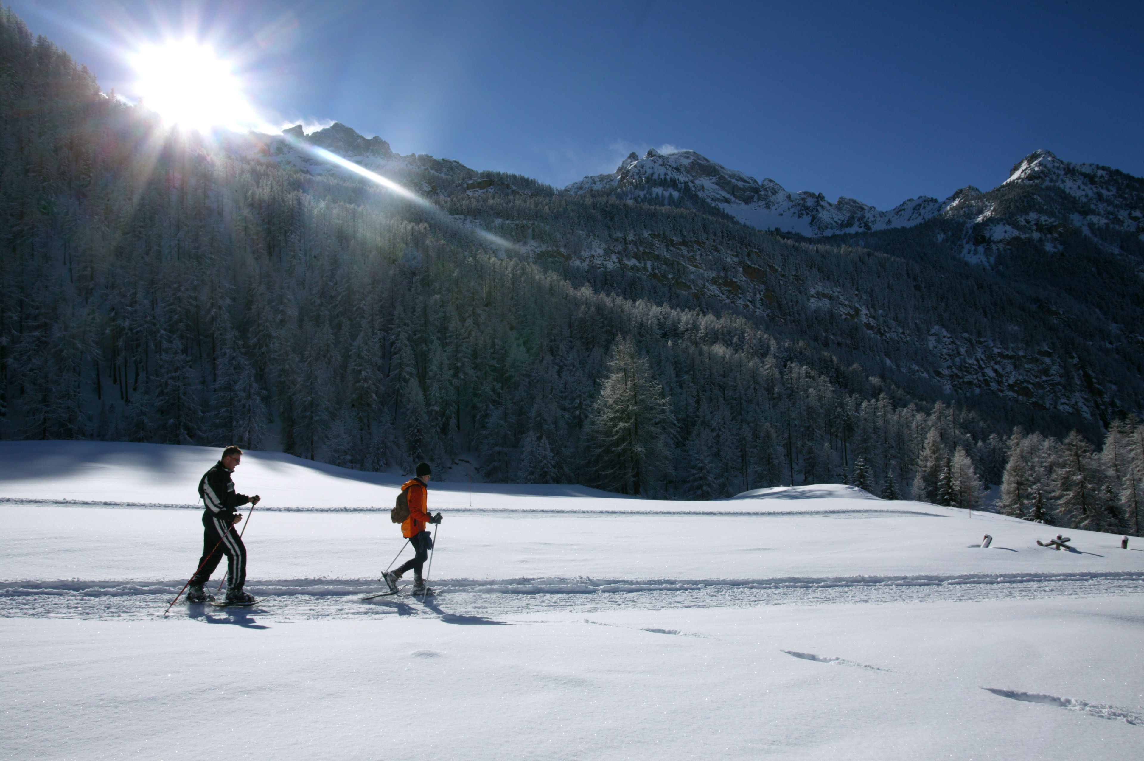 Un paysage enneigé où l’on voit deux personnes faire du ski.