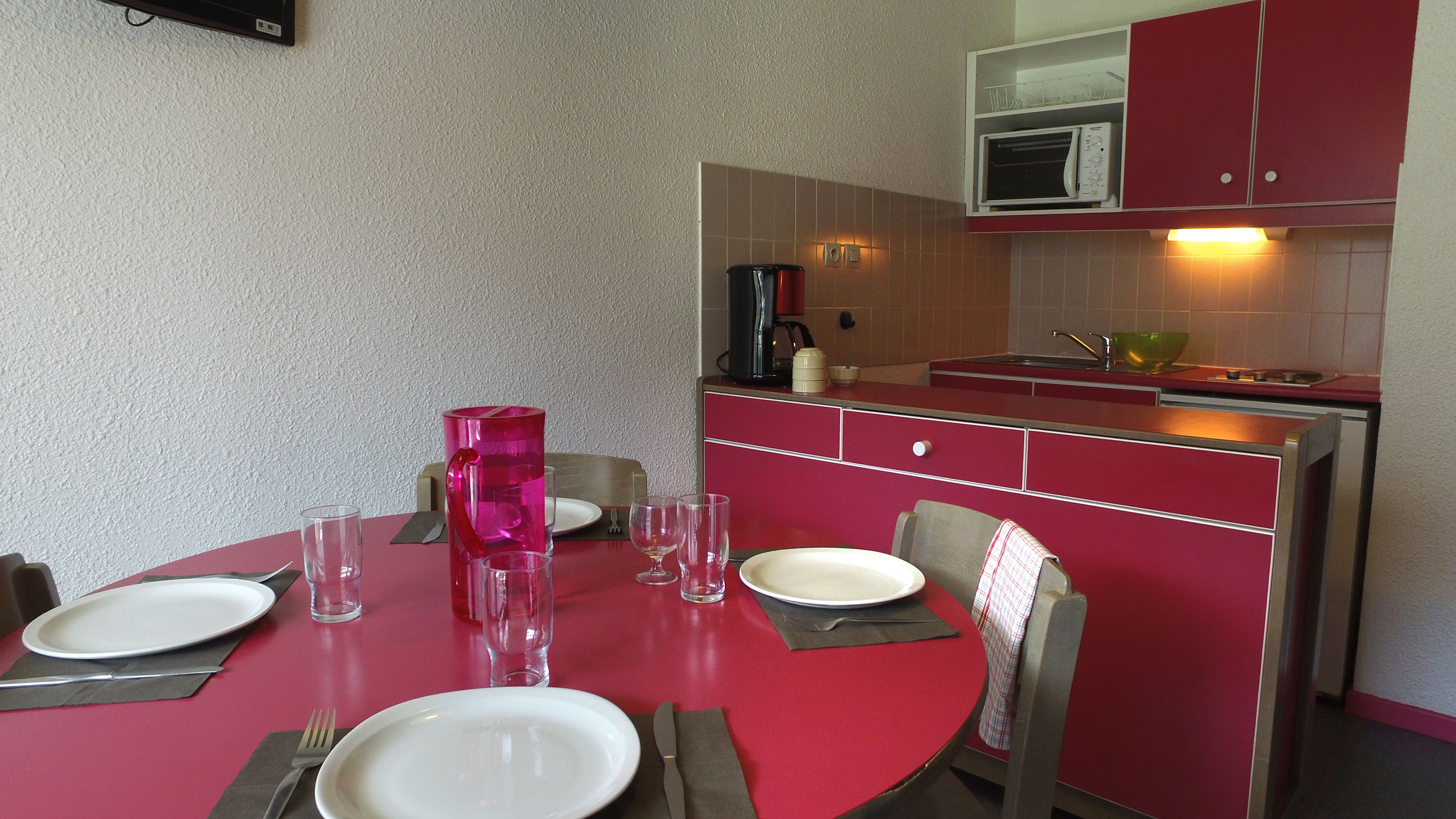 A compact kitchen with a dining area. It includes a microwave, coffee maker, and a sink.