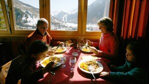 A dining table with a red tablecloth, plates of food, and glasses of water. - VVF Queyras, Ceillac-en-Queyras (Ceillac)