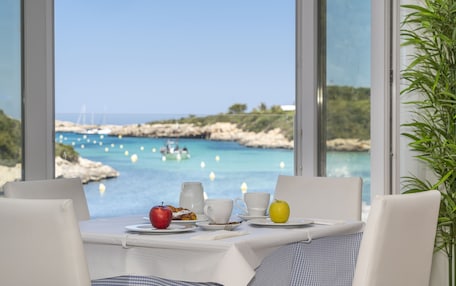 A table with breakfast items and a view of the sea.