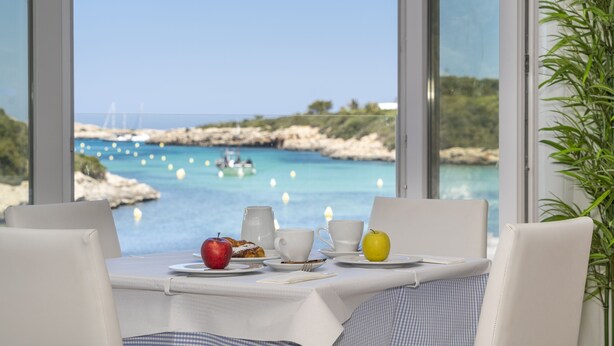 Una mesa con alimentos para el desayuno y vista al mar.