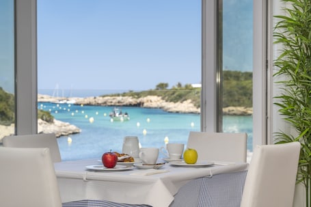 A table with breakfast items and a view of the sea.