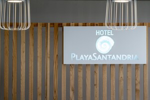 Un letrero de hotel con el nombre 'PlayasSantandria' y un logotipo con forma de caracola.