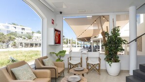 Un interior moderno con sofás color beige, una mesa redonda y una planta grande en maceta.